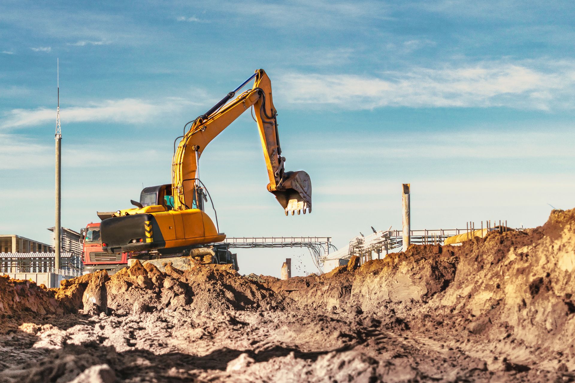 a yellow excavator is digging a hole in the dirt at a construction site .