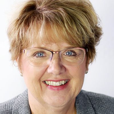 A close up of a woman wearing glasses and smiling.