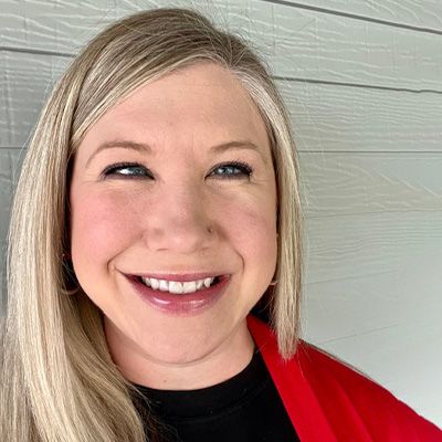 A woman wearing a red jacket and a black shirt is smiling for the camera.