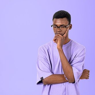 A man wearing glasses and a purple shirt is thinking.