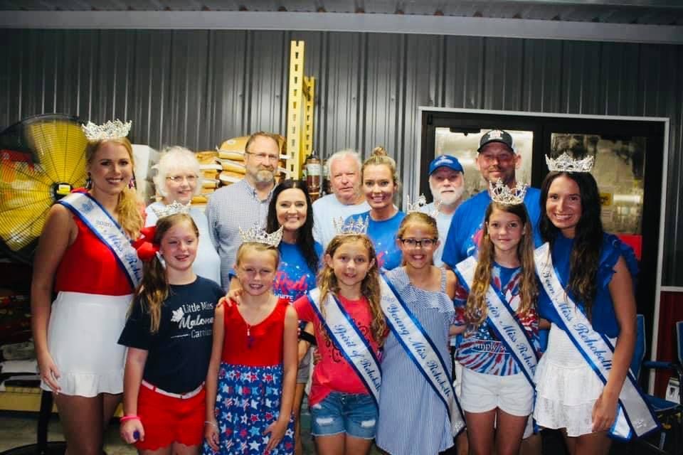 A group of people standing next to each other wearing sashes and crowns.