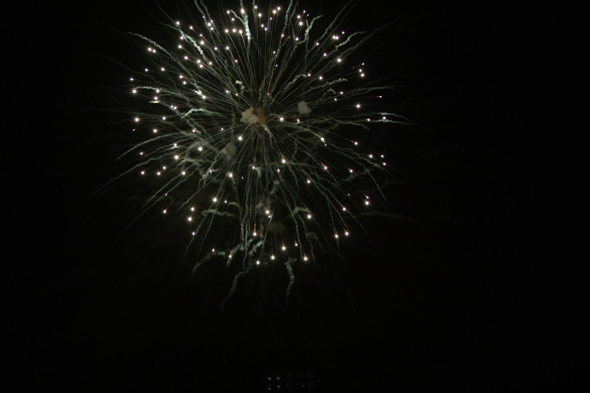 Fireworks display in the night sky. Bright white bursts radiate outwards from a central point.