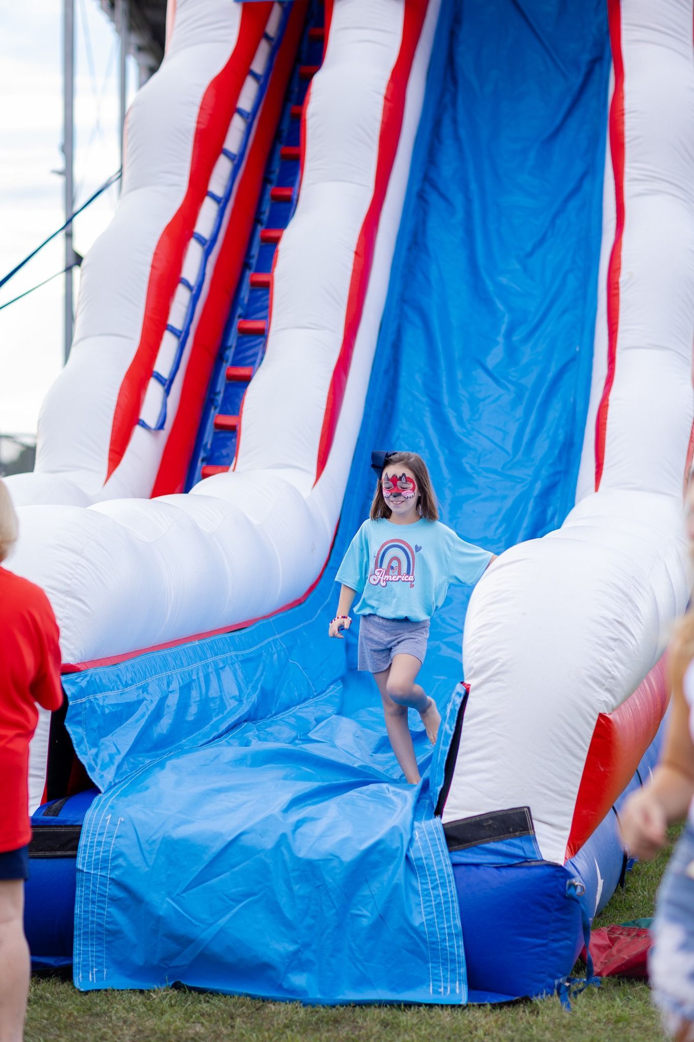 A little girl is going down an inflatable water slide.