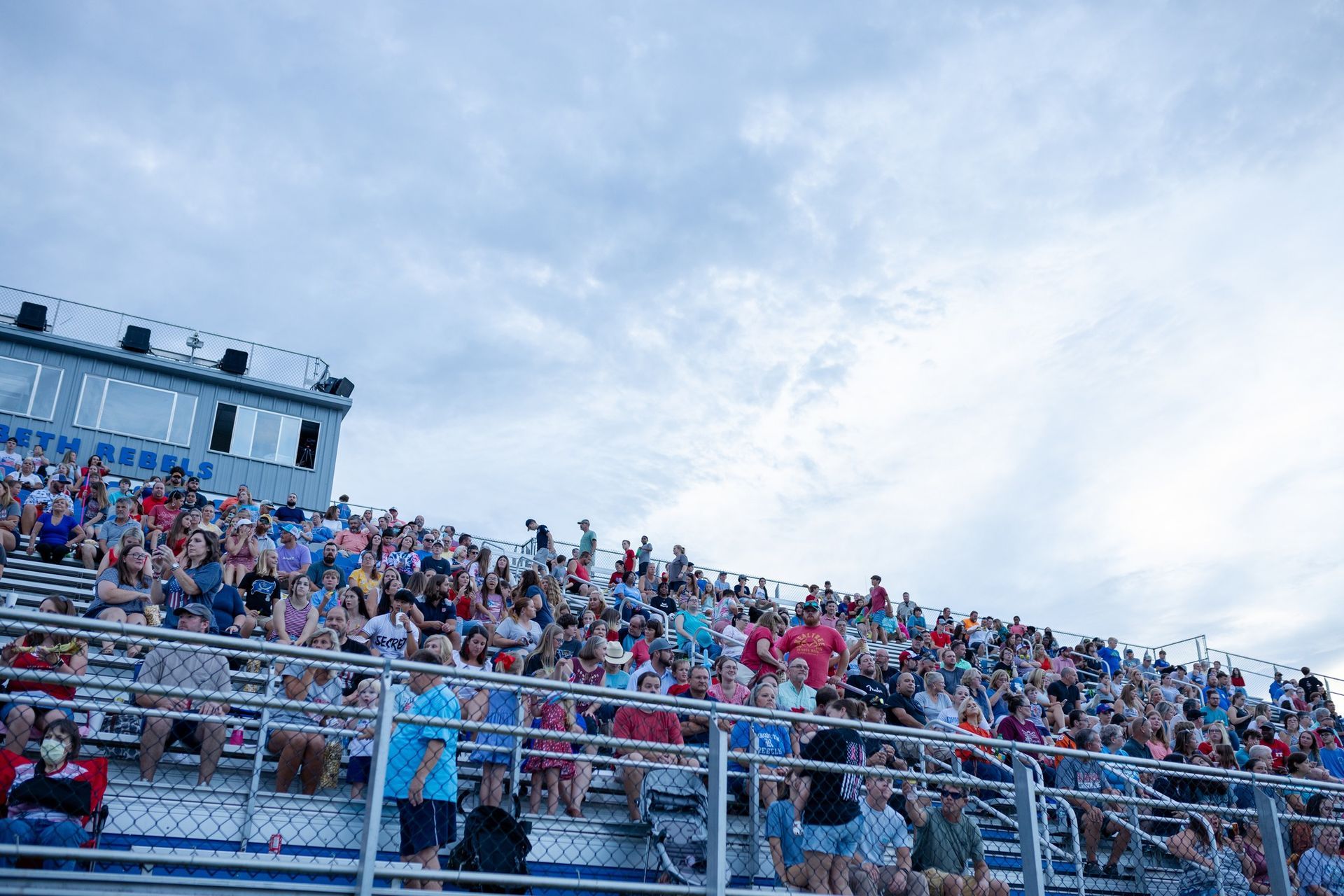 A large crowd of people are sitting in the stands of a stadium.