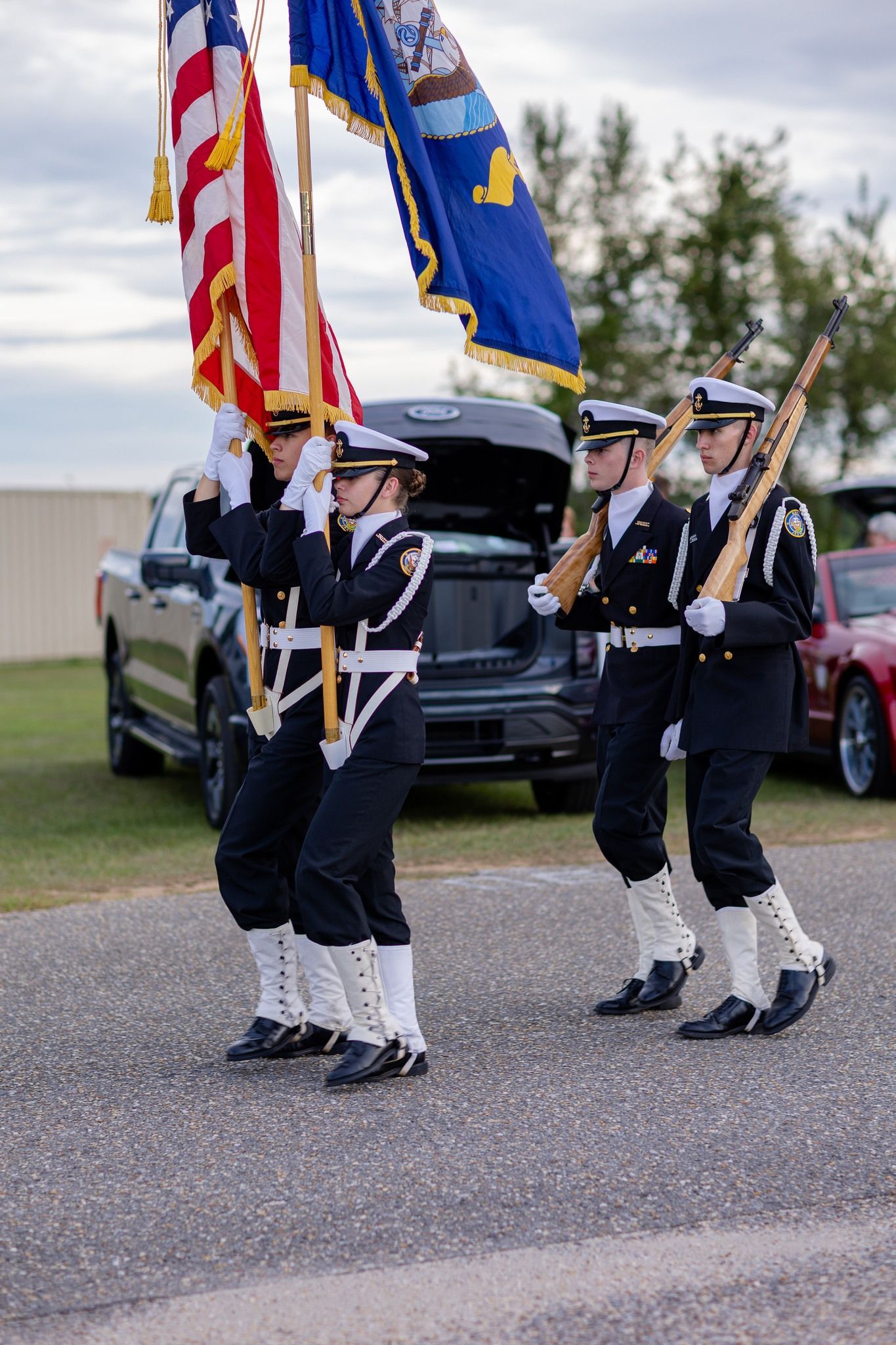 A group of soldiers are marching down the street holding flags.