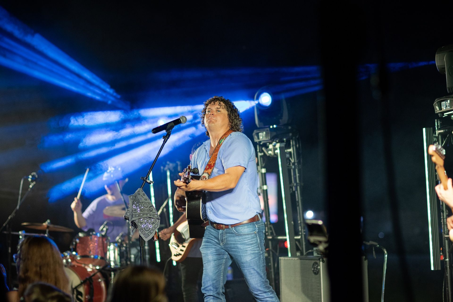 A man is playing a guitar and singing into a microphone on a stage.