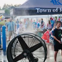A large fan is sitting under a tent at a festival.