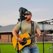 A man is playing an acoustic guitar and singing into a microphone.