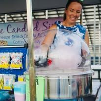 A woman is making cotton candy at a stand.