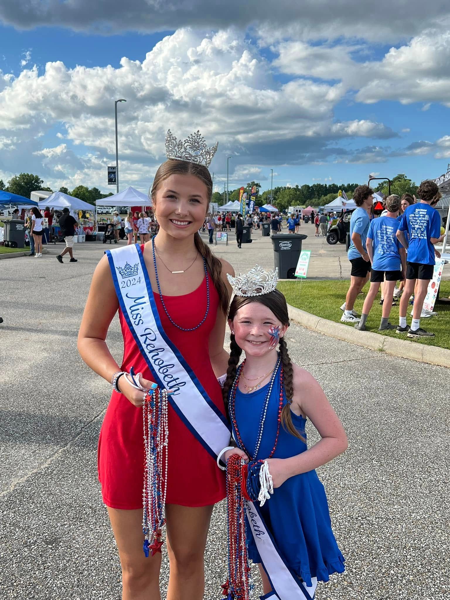 Two young girls wearing sashes and crowns are posing for a picture.