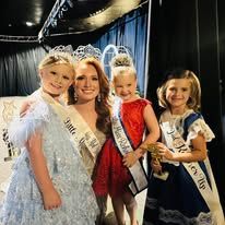 A woman and three little girls are posing for a picture.