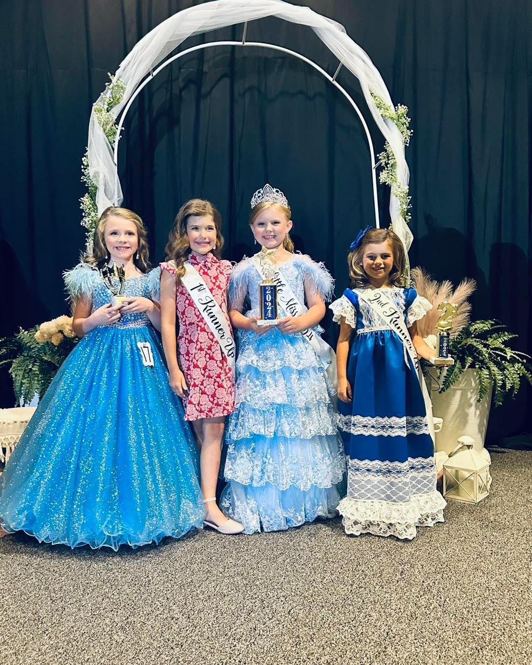 A group of young girls in blue dresses are posing for a picture.