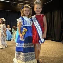 Two little girls are standing next to each other on a stage.
