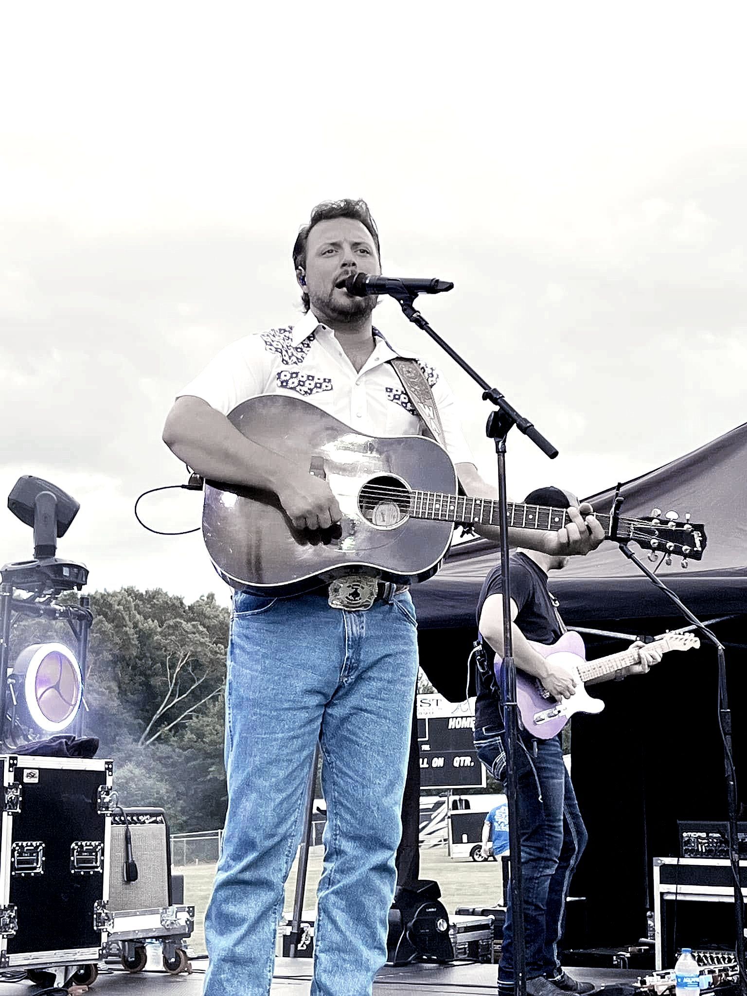 A man is playing a guitar and singing into a microphone on a stage.