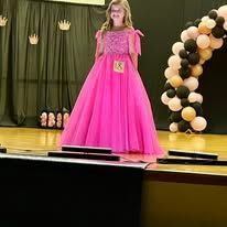 A young girl in a pink dress is standing on a stage.