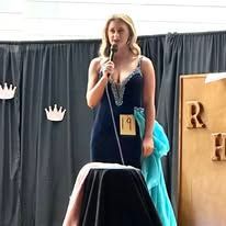 A woman in a blue dress is standing in front of a microphone.