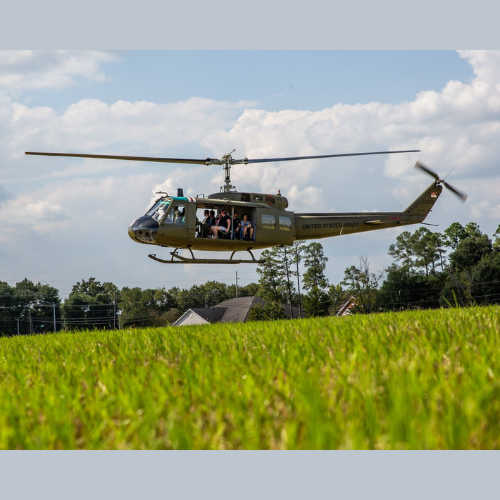 Three people standing in front of a red helicopter with the letters rj on it