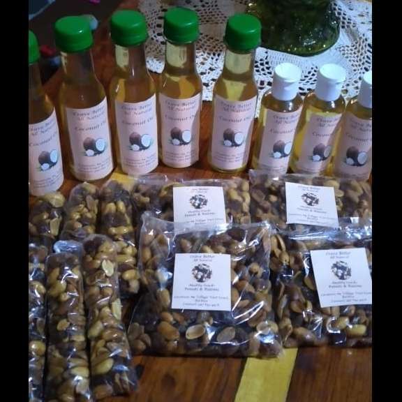 Bottles of coconut oil and bags of nuts arranged on a wooden surface.