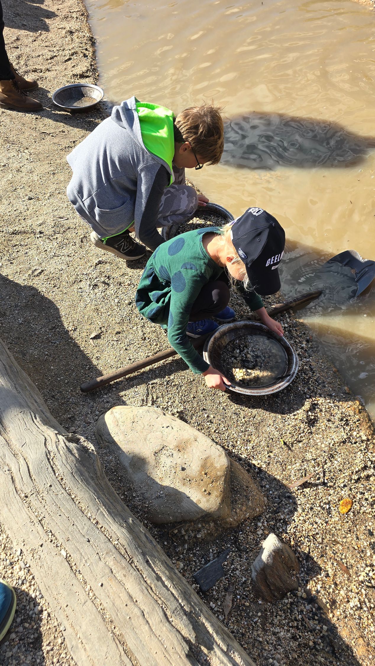 A group of children are playing in a puddle of water.
