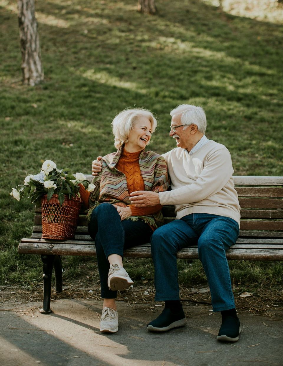 An elderly couple is sitting on a park bench.
