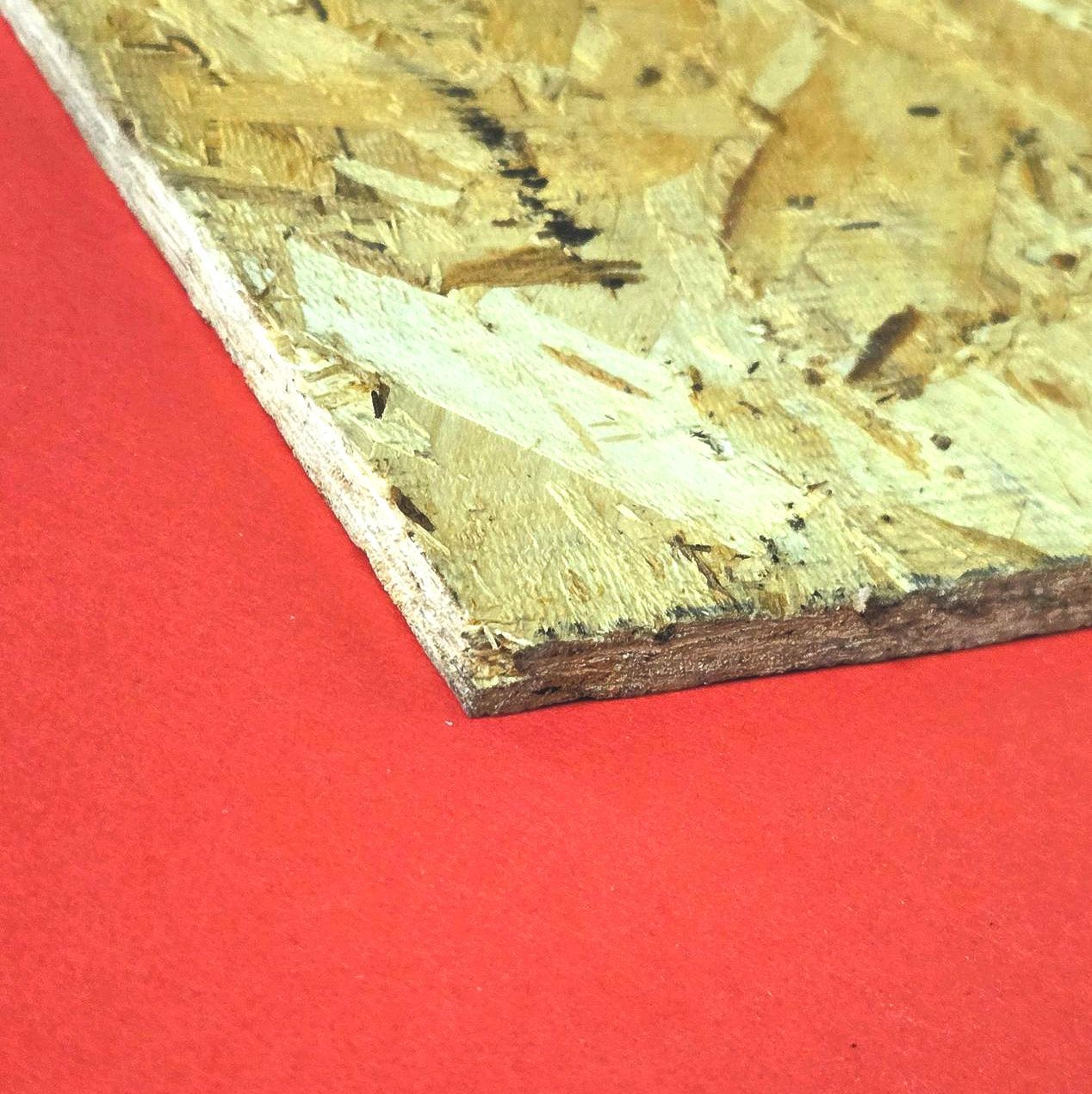 Close-up of OSB wood panel edge showing rough, splintered texture atop red surface—commonly found in construction.