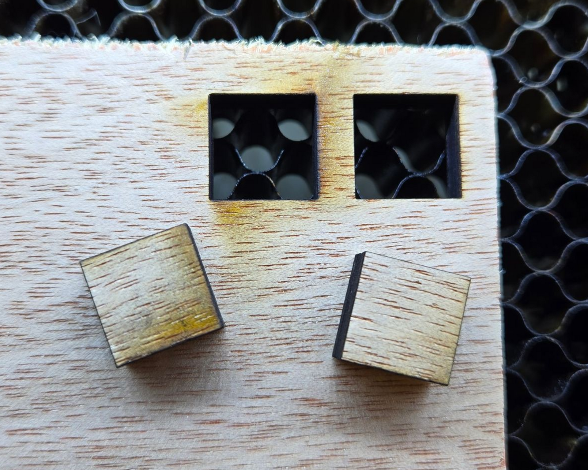 Plywood test squares: left cut with low air assist and more charring, right cut with high air assist for a cleaner edge.