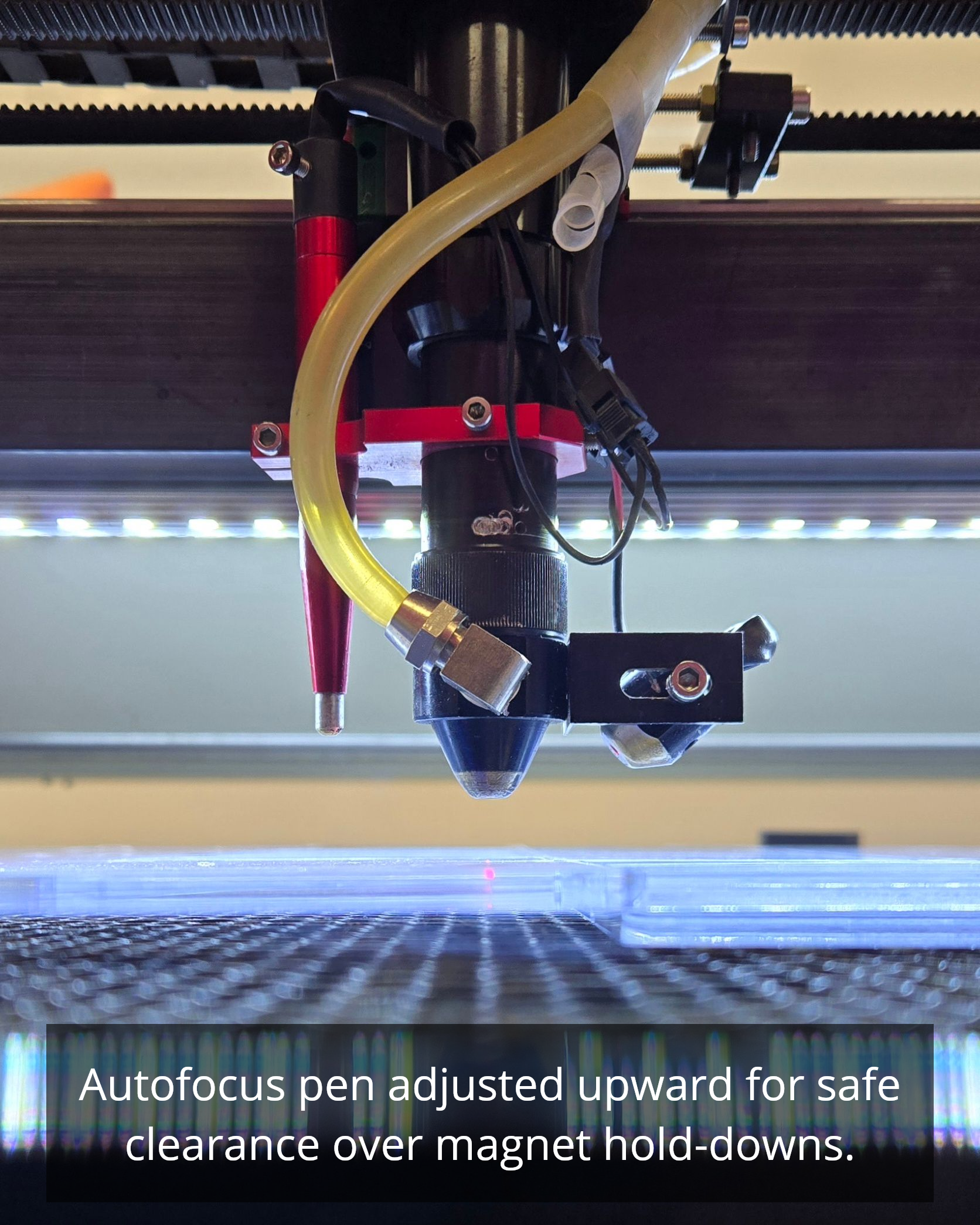 CO2 laser cutting clear acrylic with visible air assist nozzle and focused beam above honeycomb bed.