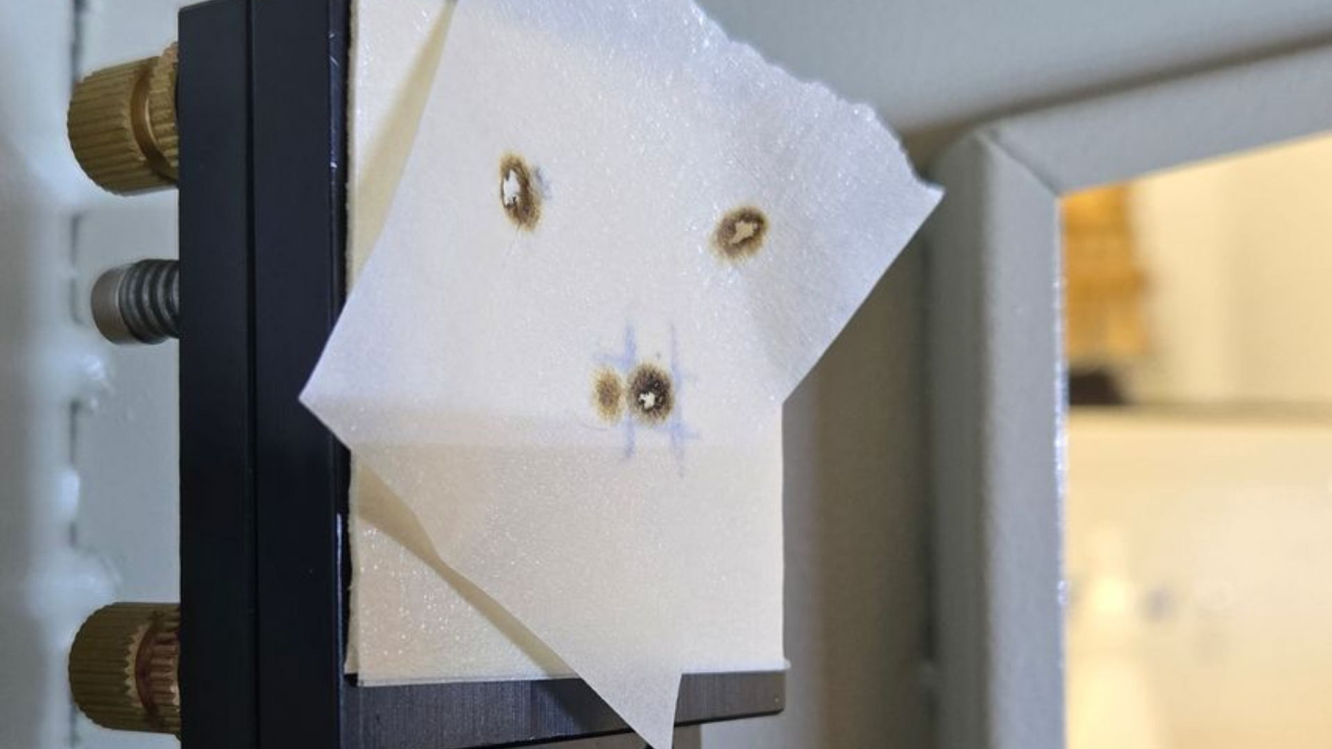 Multiple laser test burn marks showing alignment adjustment progress on mirror target