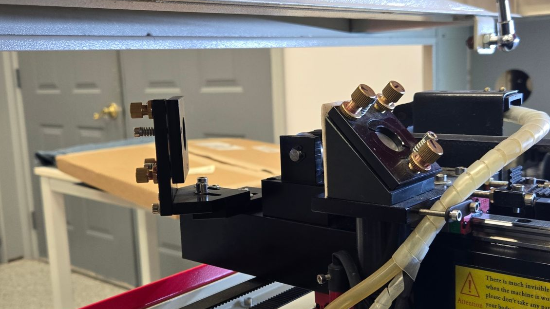 Flying optics laser mirror assembly and adjustment screws used for beam alignment