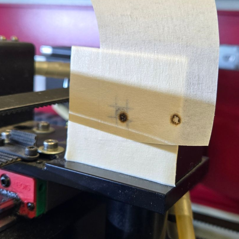 Laser beam alignment comparison showing original and shifted burn marks on tape