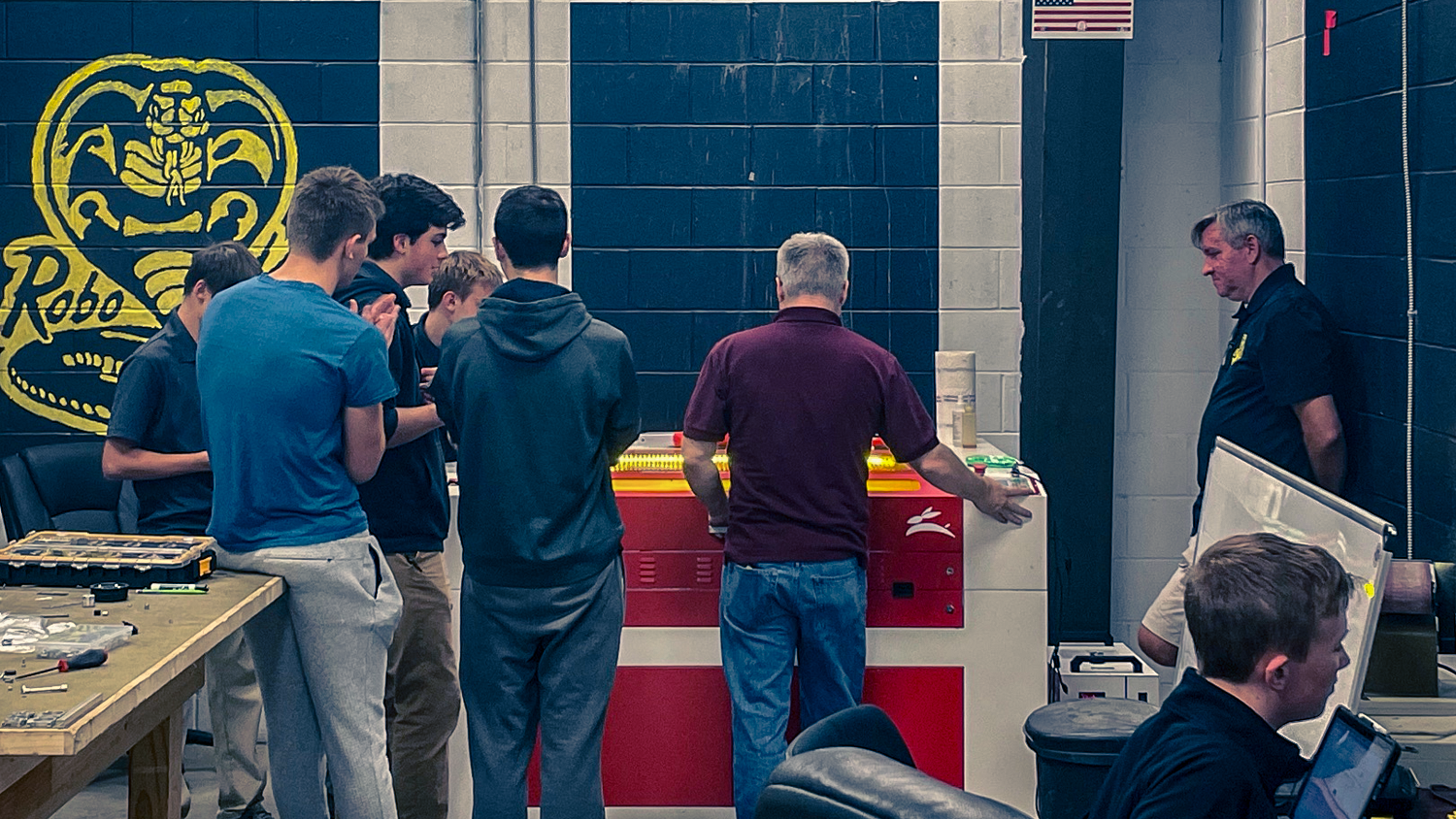 Students and instructors gather around a red and white Rabbit Laser machine during a classroom training session.