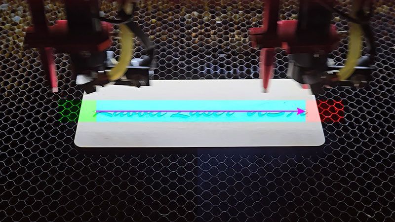 Laser engraving head moving across material at constant speed during the active engraving pass.
