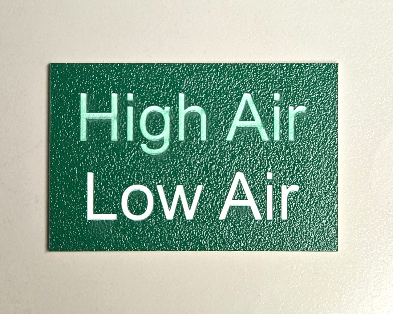 Acrylic sample engraved with “High Air” and “Low Air” to demonstrate differences in surface quality from air assist settings.