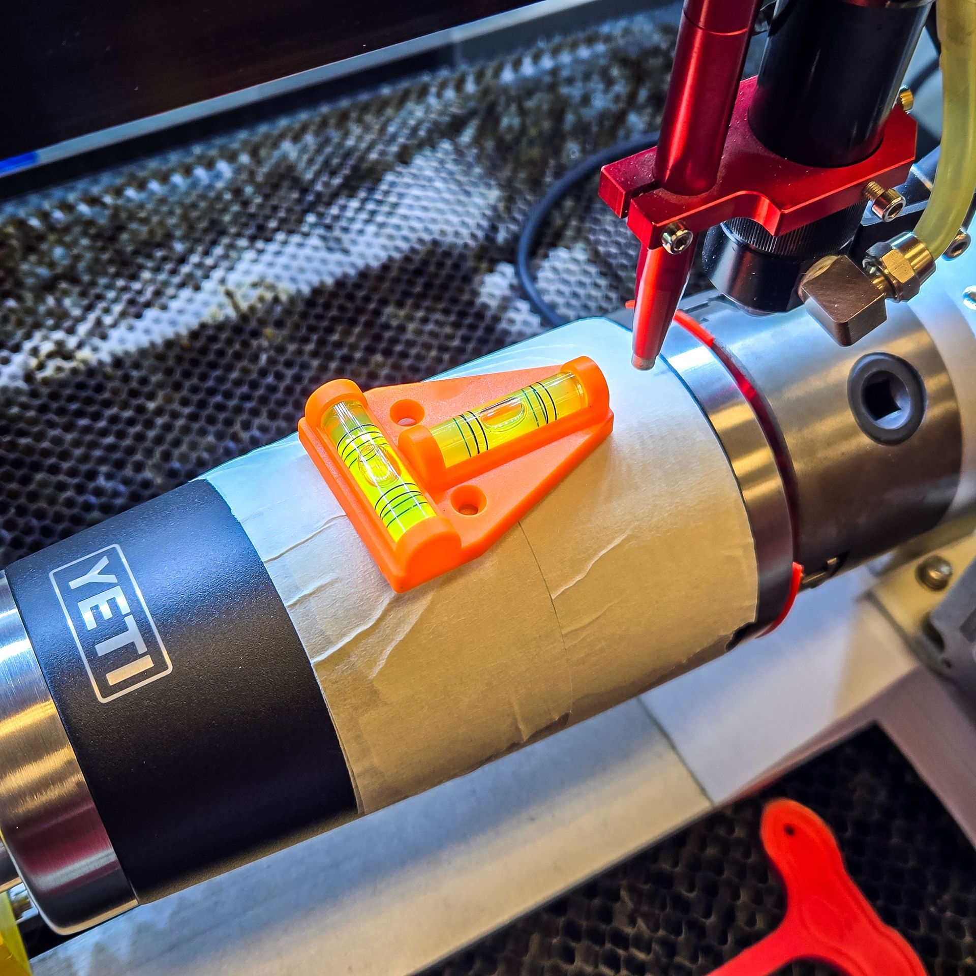Bubble level placed on a masked YETI tumbler to ensure proper alignment in a chuck rotary.