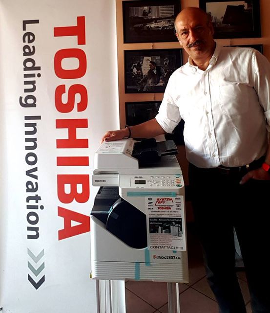 un uomo, una stampante e un poster Toshiba