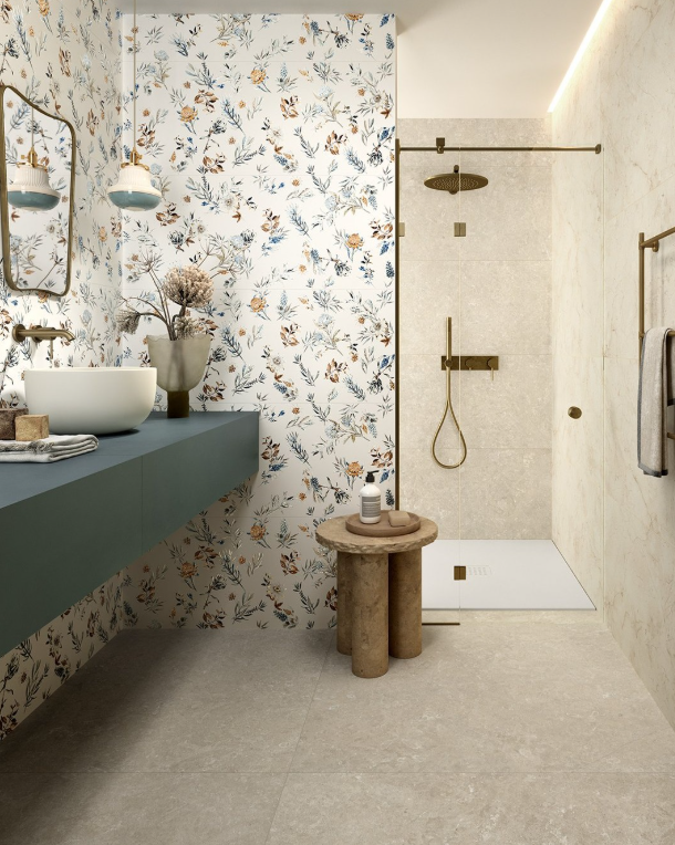 Bagno moderno con carta da parati floreale, mobile lavabo color verde acqua, pavimento in pietra e cabina doccia con rubinetteria in ottone.