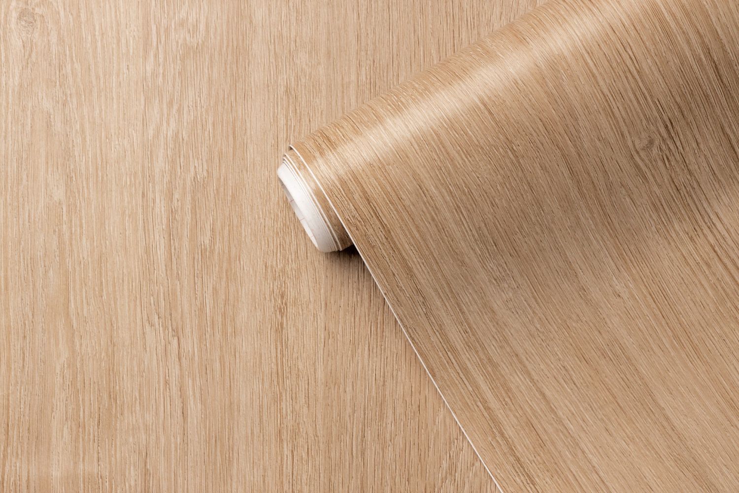 Roll of light brown wood-grain contact paper unfurling on a flat surface.