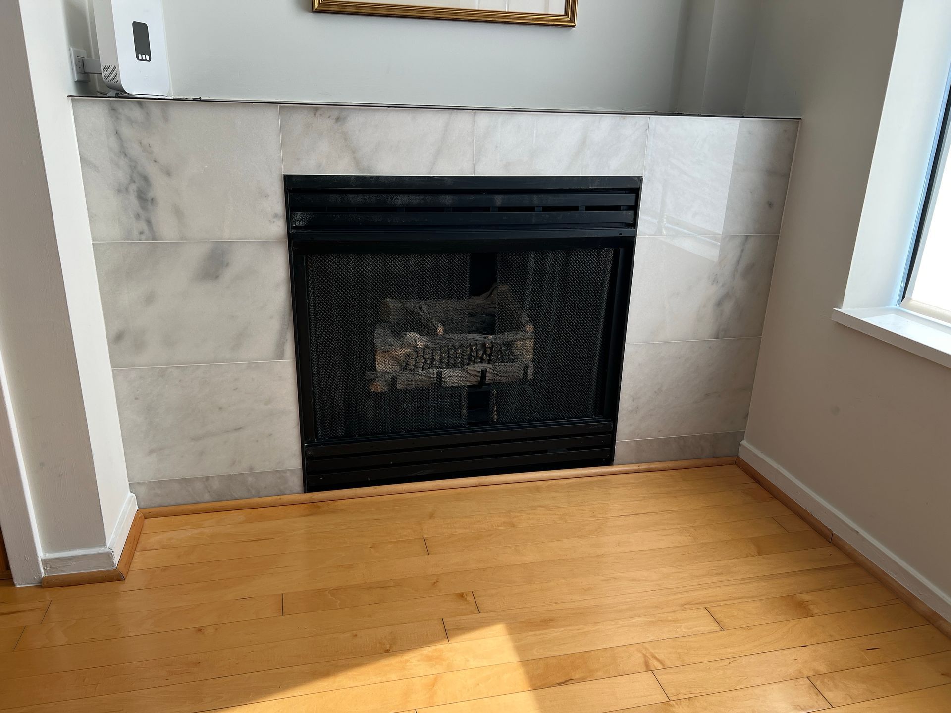 Fireplace with marble surround, black screen, and wood floor.