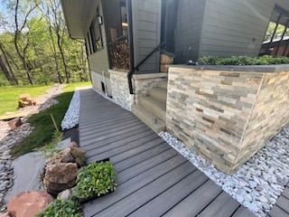 A gray ramp leads to a house with stone accents and landscaping.