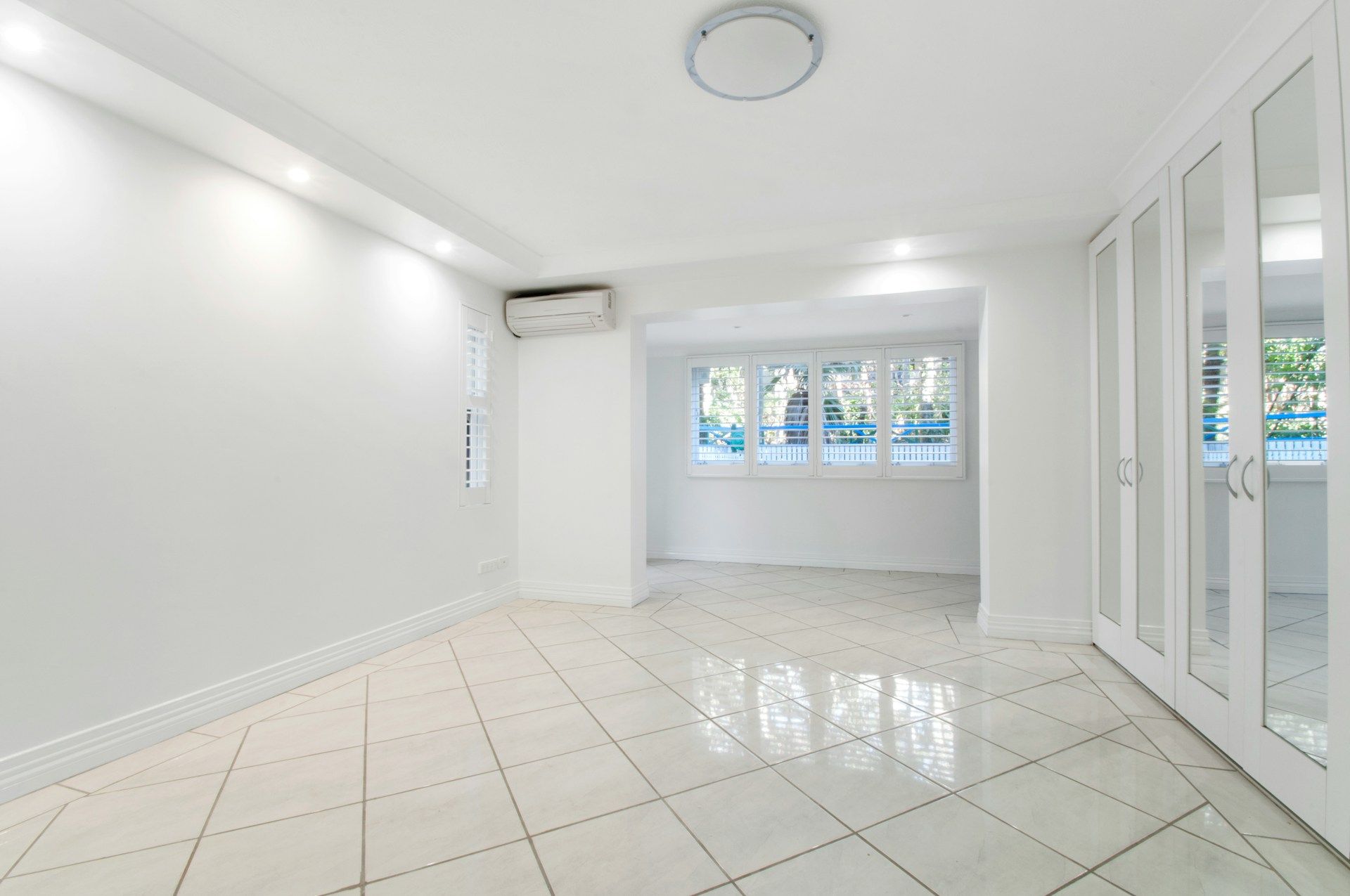 Empty white room with tiled floor, built-in closet, and a window.