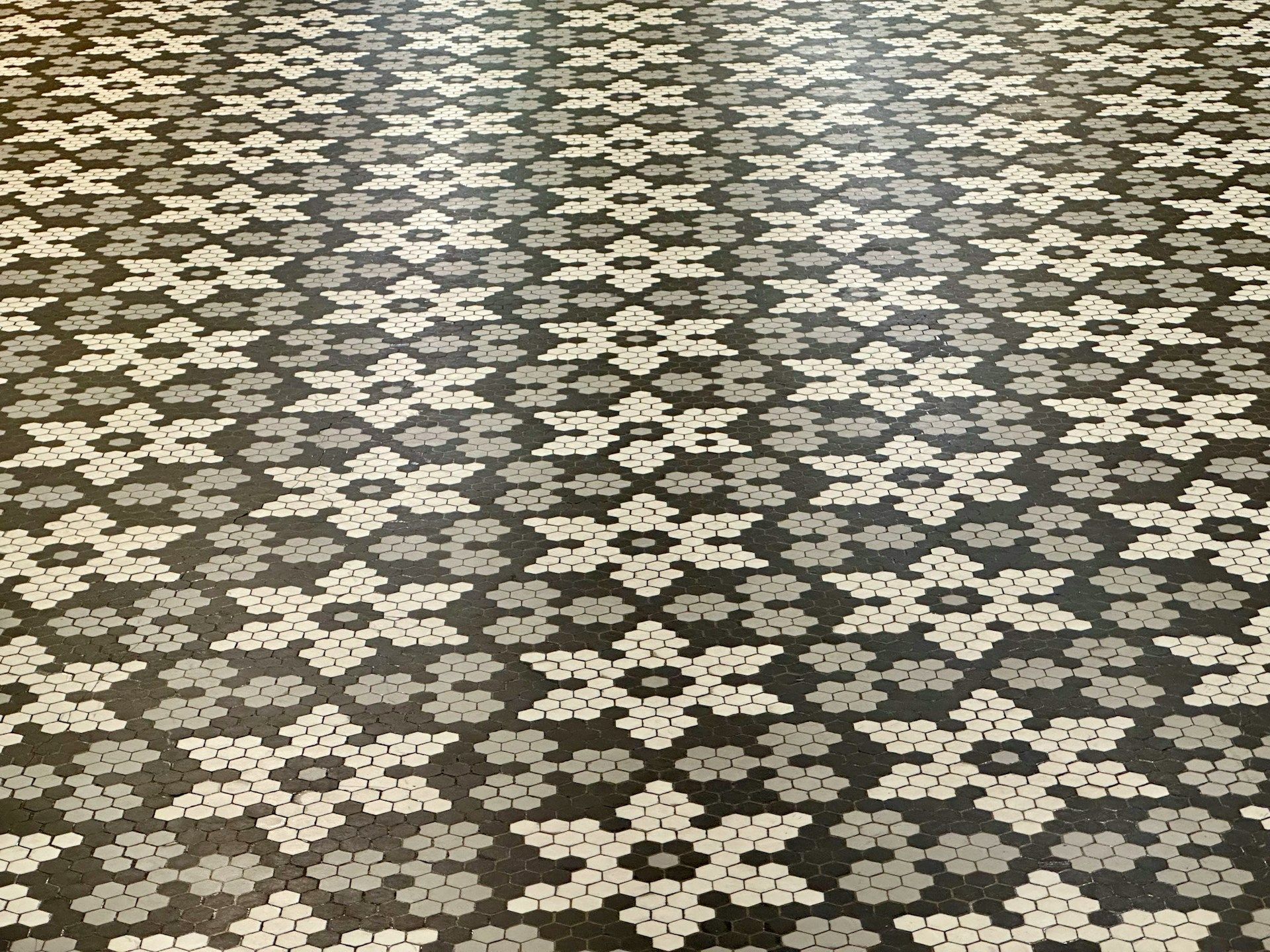 Close-up of a tiled floor with a geometric black, gray, and white snowflake pattern.