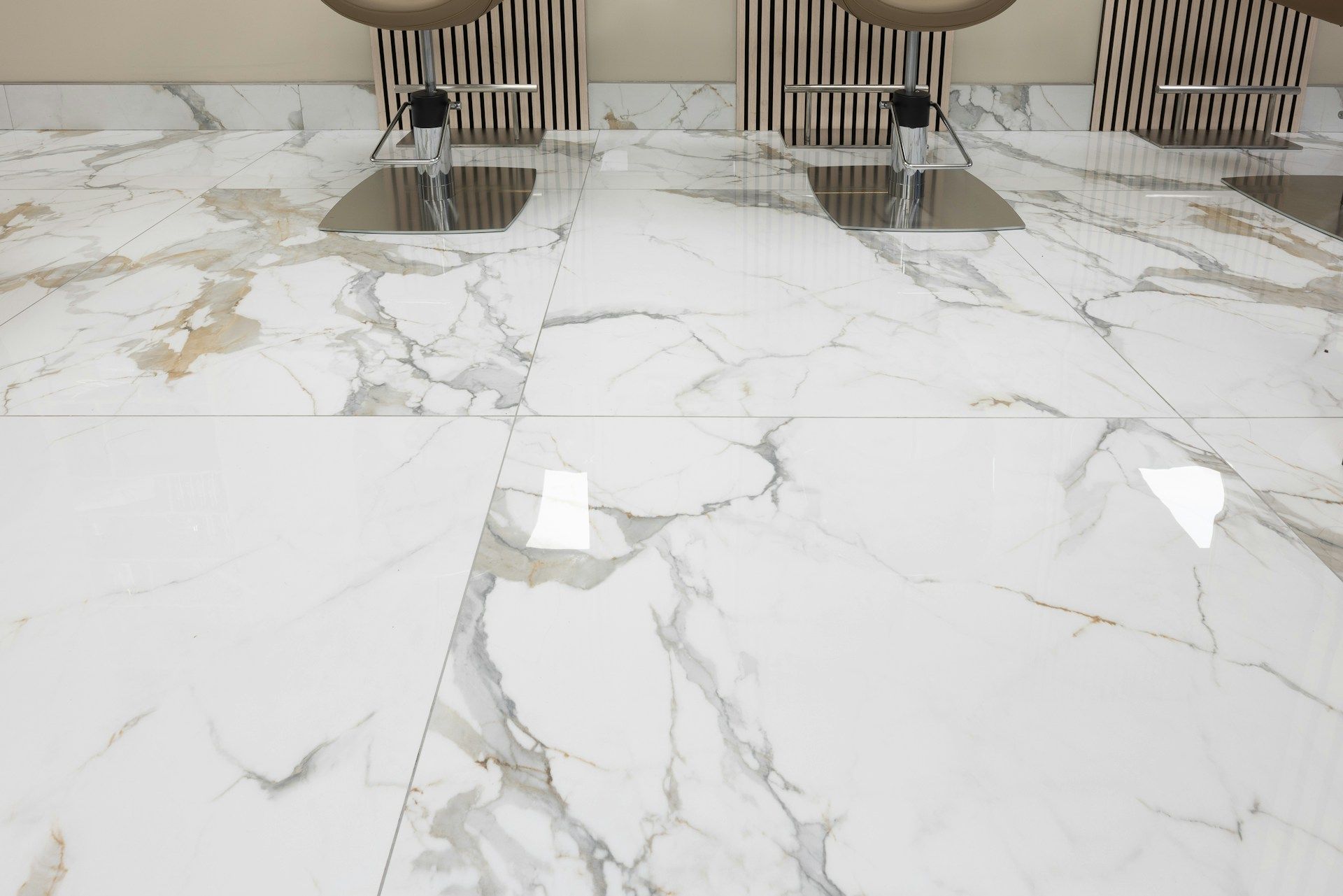White marble tiled floor with silver fixtures and a wood-slat wall background.