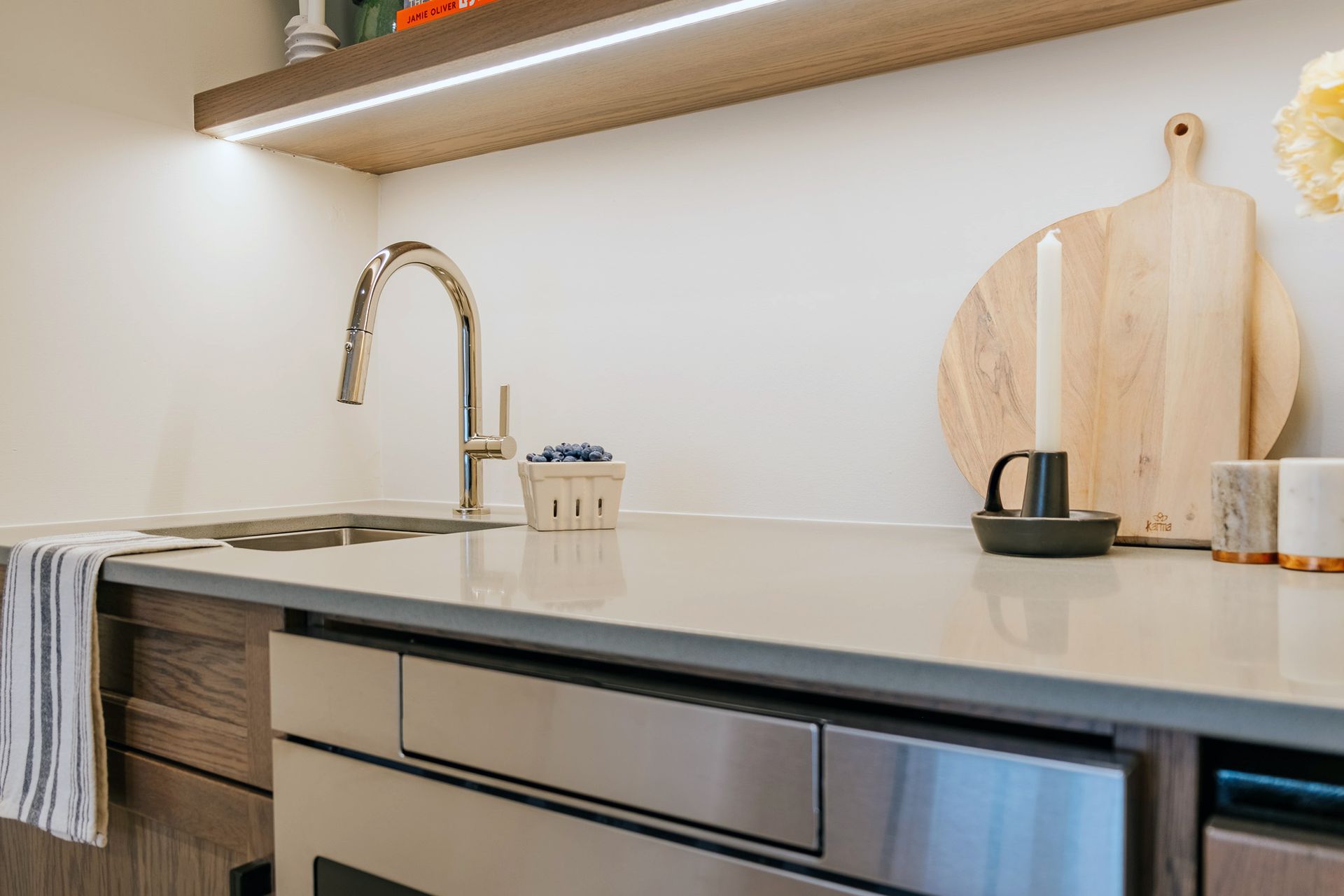 A kitchen counter with a sink, dishwasher, and cutting board.