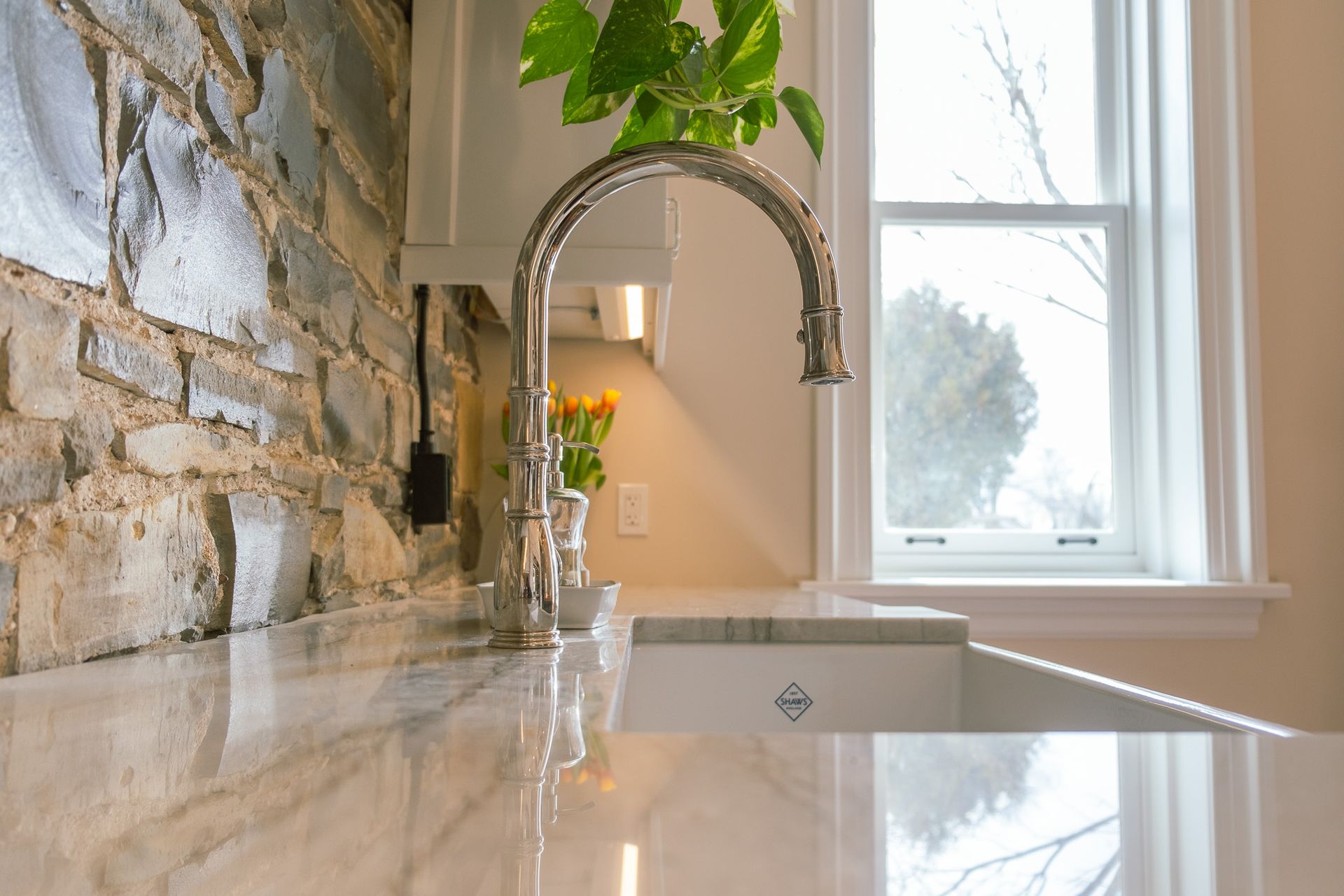 A kitchen sink with a faucet and a window in the background.