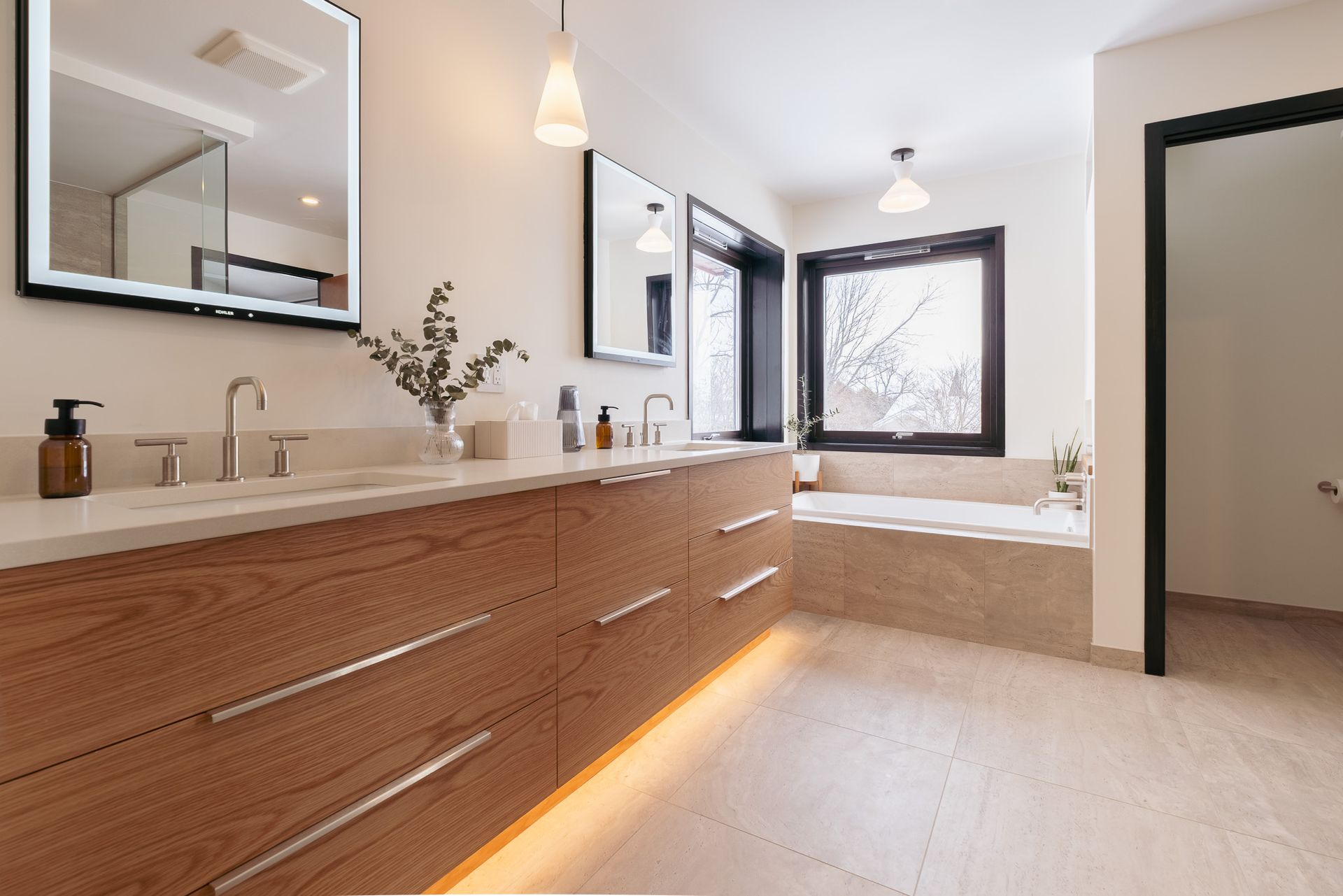 A bathroom with two sinks, two mirrors, a tub and a window.