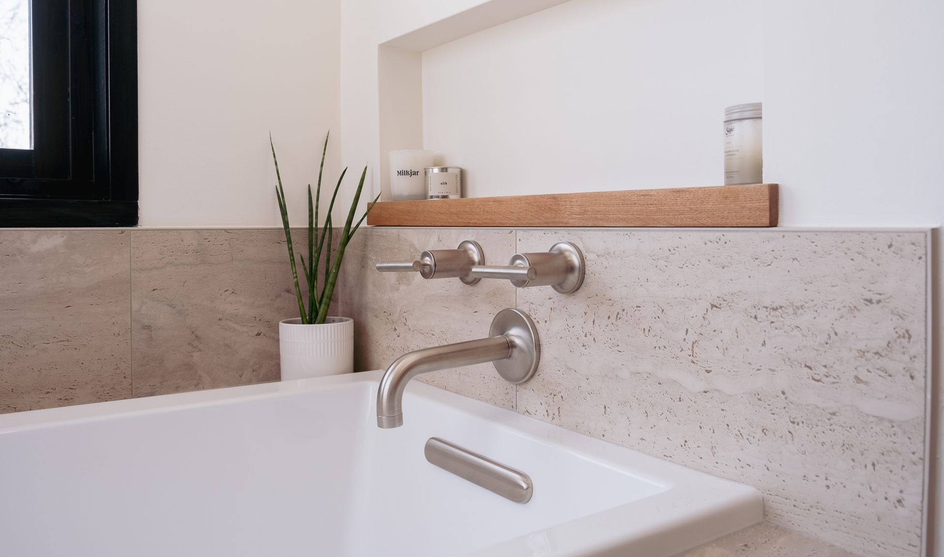 A bathtub and a plant on the wall.