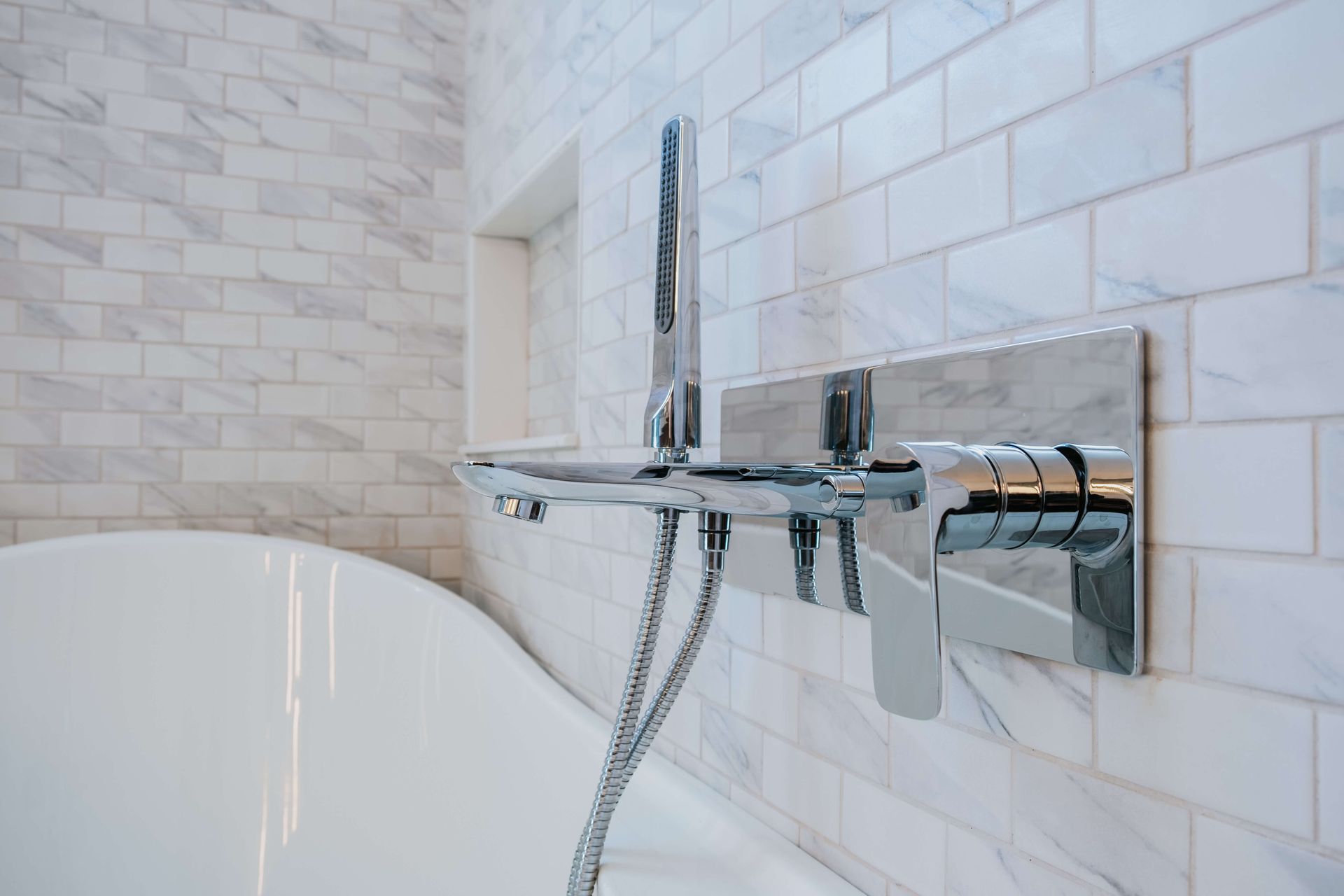 A shower with white tiles and a shower head.