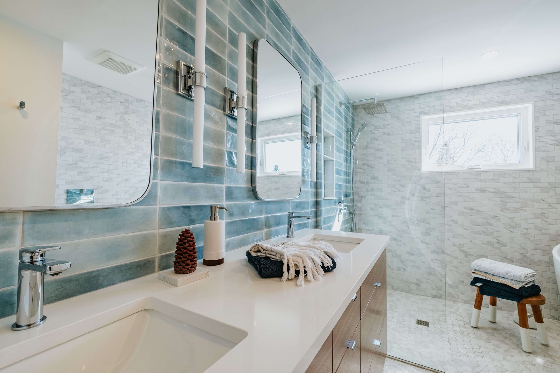 A bathroom with two sinks , two mirrors and a walk in shower.