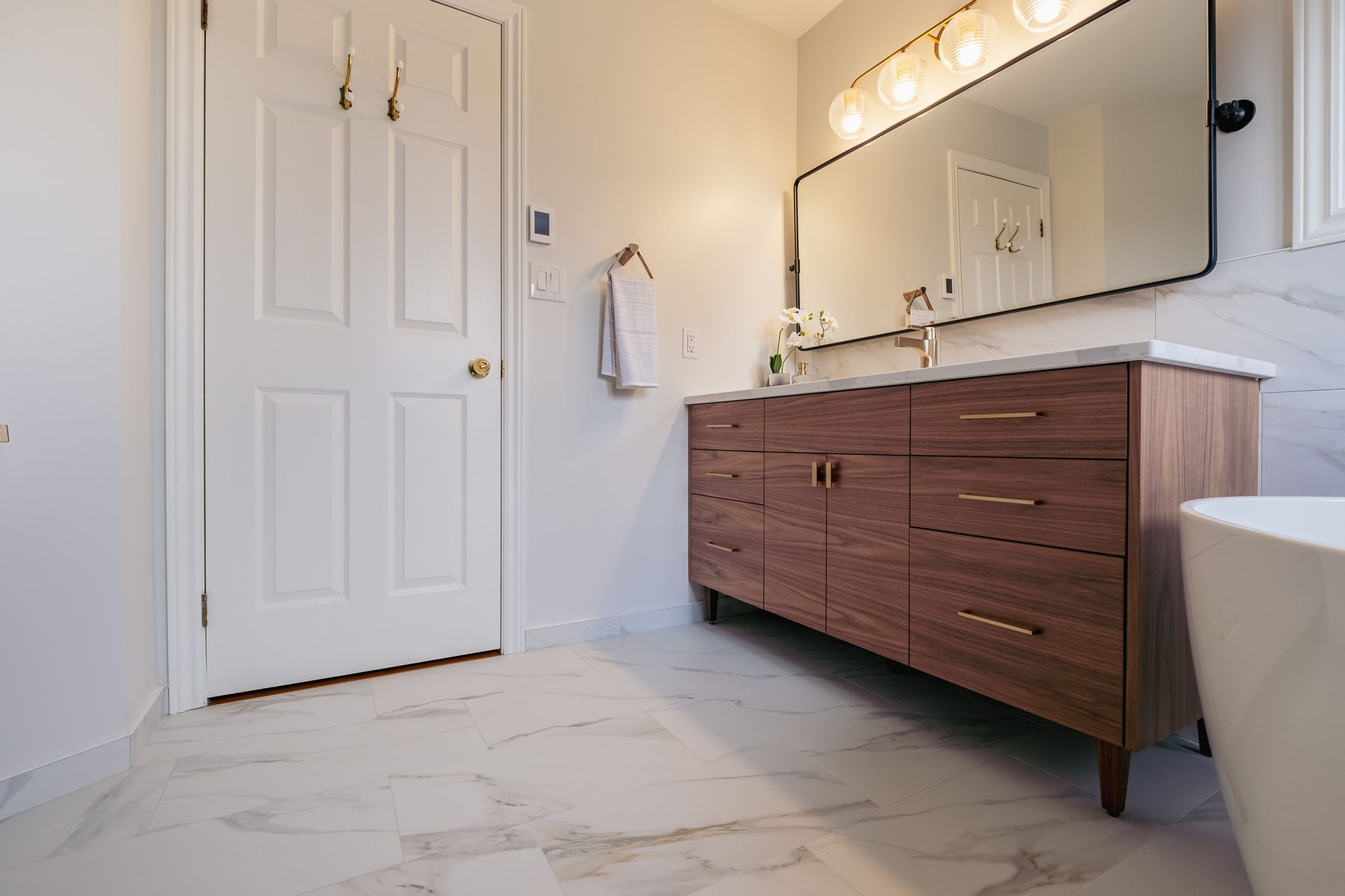 A bathroom with two sinks, a mirror and a tub.