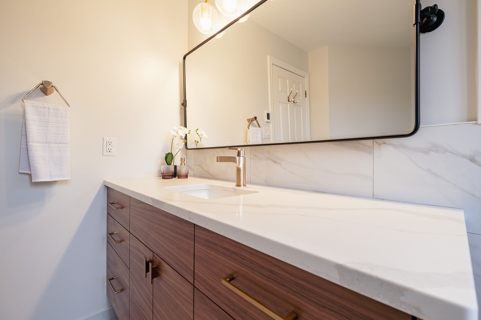 A bathroom with a sink, mirror and cabinets.